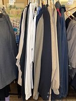 Photo showing various men's suit jackets and shirts on hangers including beige, gray, navy colors
