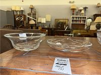 Two clear Orrefors glass bowls displayed on a wooden table, shown from side angle