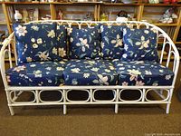 Front view of white rattan porch sofa with seat and throw cushions