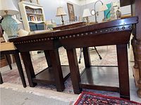 Two matching wooden side tables with nailhead trim on the edges, shown side by side.