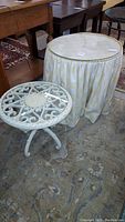 Photo of both side tables showing the resin table and the fabric-covered table with glass top on a rug.