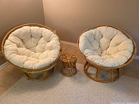 Two papasan chairs flanking small bamboo side table, front view