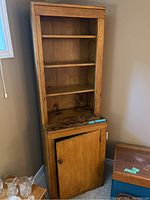 Full view of antique wooden shelving unit with cupboard door open, showing weathered wood and surface stains.