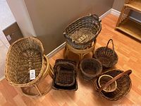 Overall view of the baskets arranged on and around two bamboo stools on wooden floor near wall corner.
