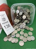 Top view of a plastic container filled with approximately 200 Canadian nickels spilling out, with visible coin details.