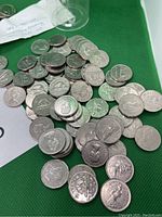 Pile of Canadian nickels showing typical circulated silver tone and designs such as beaver and Queen Elizabeth II.