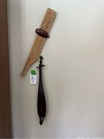 Two musical instruments hanging on a wall, a pan flute and a stringed instrument, tagged with lot number 25.