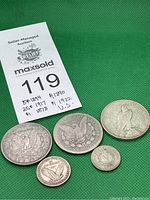 Group shot of five coins on green background with lot card