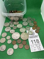 Wide view of plastic tub of coins and laid-out silver dollars, half-dollars, quarters, dimes, pennies