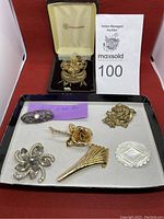 Seven vintage brooches on display including filigree, silver-tone, and gold-tone pins.
