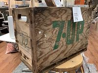 Side view of vintage 7up wooden crate showing green 7up branding and cut-out handle.