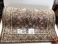 Top view of rolled carpet runner displaying detailed floral pattern in dusty rose, black, beige, and cream.