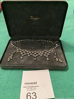 Full set displayed in original black velvet-lined box showing necklace and matching earrings.