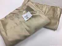 Pair of beige faux silk drapery panels folded, showing fabric texture and sheen.