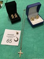 Photo of the full jewelry lot including gold crucifix necklace, two pairs of gold earrings, Australian opal and diamond earring, and silver hoop earring.