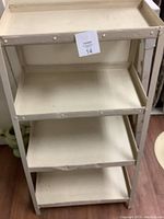 Full view of vintage metal shelf unit showing four angled shelves and structural frame.