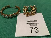Photo showing the rhinestone bracelet and matching brooch placed on a green surface with auction lot number 73 card.