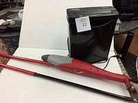 Side view of Swing Line shredder and two red-handled mops on white backdrop