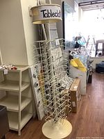 Full view of the coated metal spin rack with multiple wire baskets and plastic base and top labeled 'Tablecloth'