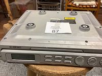 Top view of the silver Curtis undercabinet CD radio showing the device's flat top surface and rubber feet for mounting.