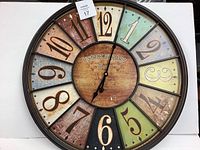 Full view of the 24-inch metal wall clock showing the colored numbered sections and center label 'Bistrot de Paris'.