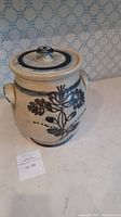 Handmade pottery urn with floral decoration and lid on top, showing general shape and style