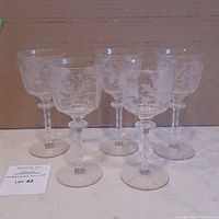 Group of 5 clear wine glasses with etched floral motif design, arranged in a semi-circle, shown from front view to highlight etching and condition.
