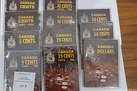 Overview of nine coin folders laid out on table, covers showing denominations and crests