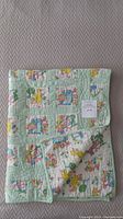 Folded vintage Sesame Street baby quilt showing front pattern squares and pastel green border on neutral background.