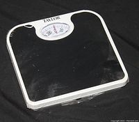 Taylor bathroom scale showing black textured platform, white frame, and analog dial display.