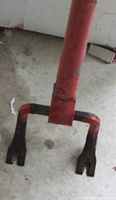 Top view of a metal deck wrecker tool with red handle and black forked end showing wear and usage marks.