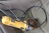 Yellow DeWalt rotary tool grinder with metal cutting disc and coiled power cord