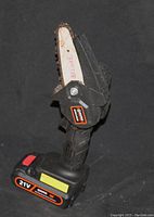 Handheld cordless mini chainsaw with 10-inch chain blade and attached 21V rechargeable battery pack, black body with orange label.