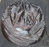 Photo of folded pop up hunting blind in black circular carrying case with Ameristep brand label and zipper pocket visible.