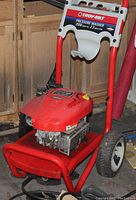Front side view of Troy-Bilt pressure washer with red frame, engine, control handle, and wheels