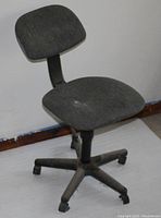Front-side view of a gray fabric typist chair with a rounded backrest and seat, mounted on a black five-star base with casters.