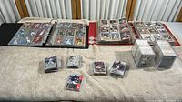 Two 3-ring binders open showing baseball and football cards, with several piles of loose cards and cards in slabs on table