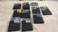 Overview of 12 Nintendo and Super Nintendo game cartridges arranged on beige fabric surface.