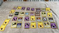 Full spread of 35 Pokémon trading cards including multiple energy cards, character cards, and trainer card laid out on a beige surface.