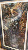Close up photo of the framed Black Canyon Xpress print showing the train crossing the wooden bridge in a canyon scene.
