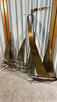 Photo showing full view of metal wall sculpture featuring three ships with large copper and patinated metal sails.