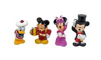 All four Disney character figures in a row: Donald Duck, Mickey Mouse holding gift, Minnie Mouse, and Mickey Mouse in magician outfit