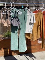 All 8 items hanging on a clothesline outdoors including pants, tops, and bras visible.