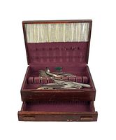 Wooden box open showing satin-lined interior and silver plated flatware inside.