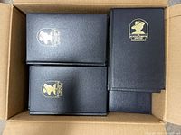 Top-down view of a box containing multiple black hardcover books with gold emblem of Agatha Christie Mystery Collection on cover.