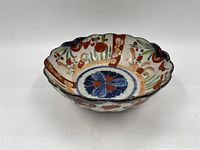 Scalloped ceramic bowl with hand-painted floral and geometric designs in blue, red, orange, and green on interior and exterior surfaces.