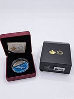 Red presentation case open showing coin in acrylic capsule and COA card