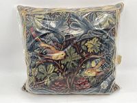 Front view of cushion showing the detailed woven bird and foliage design enclosed in packaging.