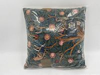 Front view of Hines cushion in plastic packaging, showing colorful bird and fruit tapestry design.