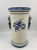 Front view of large ceramic umbrella stand with blue hand-painted floral details and blue rim accents.